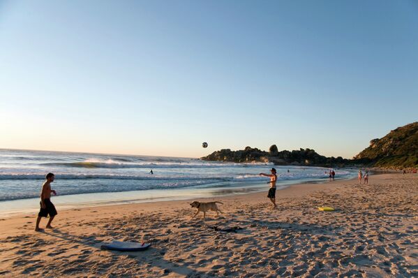 Молодые люди играют в мяч на побережье в ЮАР