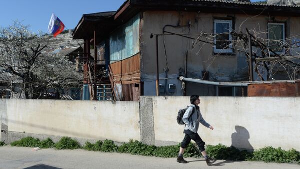 Девушка идет мимо дома на котором вывешен российский флаг на одной из улиц Бахчисарая. Архивное фото
