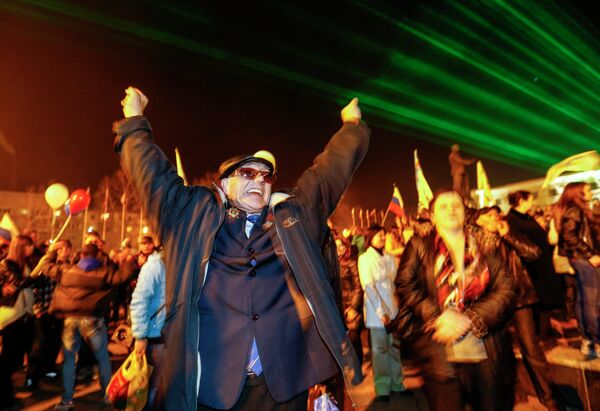 Люди наблюдают за праздничным салютом в честь присоединения Крыма к Российской Федерации на главной площади Симферополя