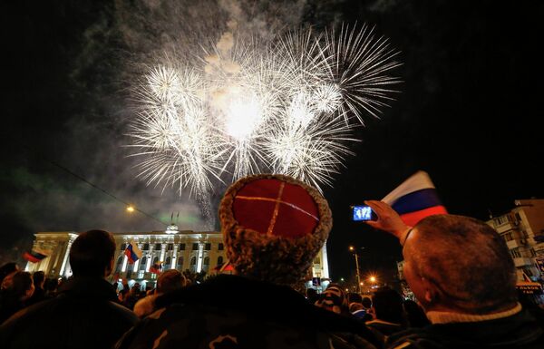 Люди наблюдают за праздничным салютом в честь присоединения Крыма к Российской Федерации на главной площади Симферополя