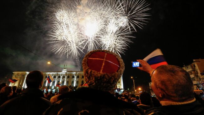 Люди наблюдают за праздничным салютом в честь присоединения Крыма к Российской Федерации на главной площади Симферополя