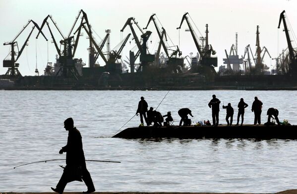 Люди ловят рыбу на пирсе в порту Мариуполя
