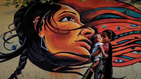 Мама с ребенком проходит мимо граффити в Мумбаи