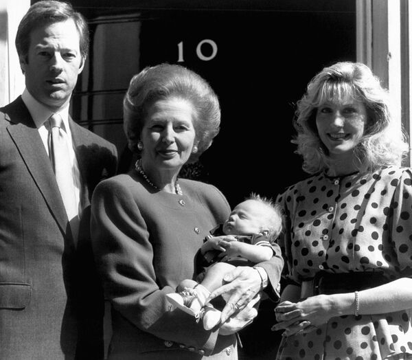 Премьер-министр Великобритании Маргарет Тэтчер держит своего внука на Даунинг-стрит в Лондоне, Великобритания