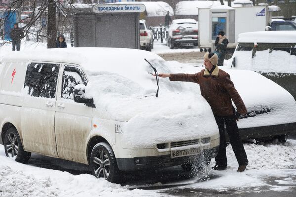Мужчина очищает автомобиль от снега