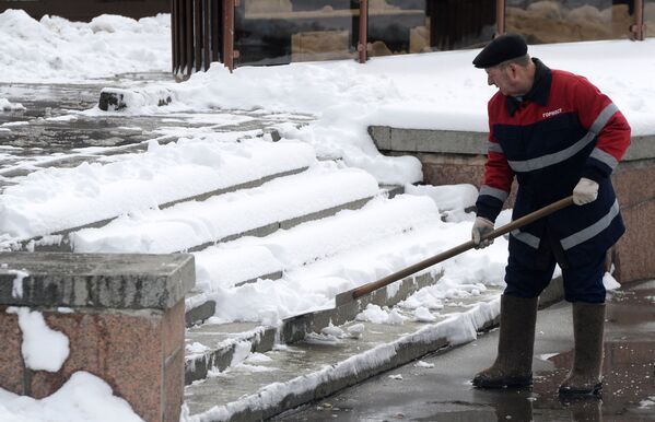 Сотрудник коммунальных служб убирает снег на улице