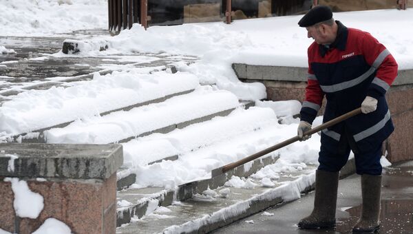 Сотрудник коммунальных служб убирает снег на улице. Архивное фото