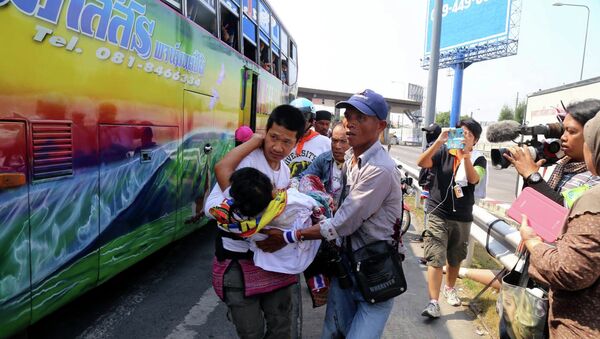 Демонстранты несут товарища, который был ранен при обстреле их автобуса в Бангкоке 1 апреля 2014. Фото с места события