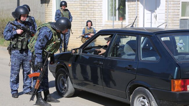 Сотрудники полиции досматривают автомобиль на месте проведения контртеррористической операции у частного дома в Буйнакске. Фото с места события