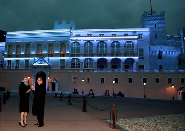 Княжеский дворец в Монако подсвечен синими прожекторами в рамках акции Light It Up Blue. На переднем плане - Принц Альберт II и его жена Шарлен Уиттсток