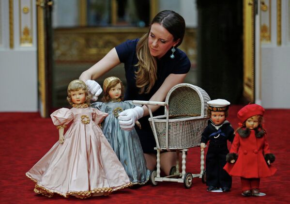 Куратор Анна Рейнольдс вместе с игрушками, принадлежащими королеве Англии Елизавете Второй и ее сестре принцессе Маргарет