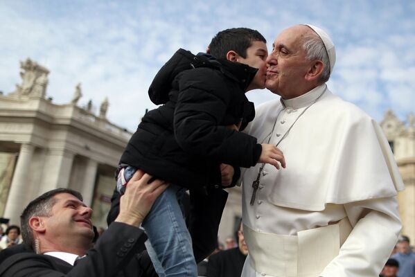 Папа Римский Франциск целует ребенка на площади Святого Петра в Ватикане