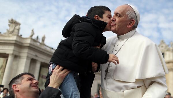 Папа Римский Франциск целует ребенка на площади Святого Петра в Ватикане