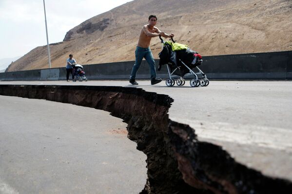 Жители идут вдоль поврежденной в результате землетрясения дороги в чилийском городе Икике