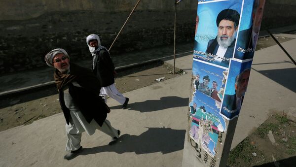 Мужчины смотрят на плакат кандидата в президенты Афганистана