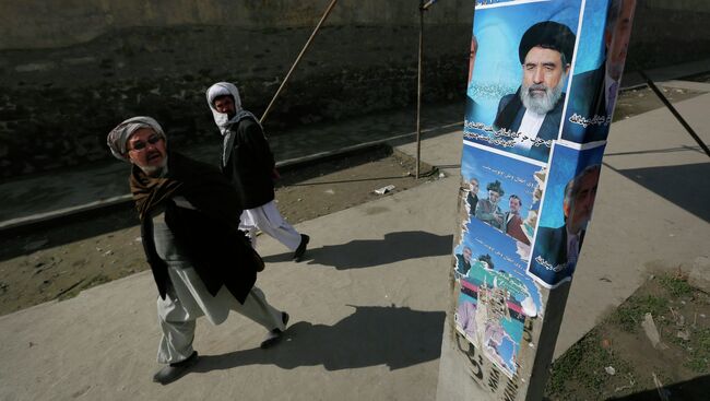 Мужчины смотрят на плакат кандидата в президенты Афганистана