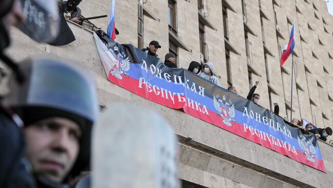 Участники митинга в Донецке, организованного сторонниками референдума о статусе региона, на здании областной администрации