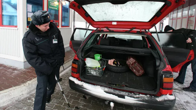 Пограничник досматривает автомобиль на автомобильном пункте. Архивное фото