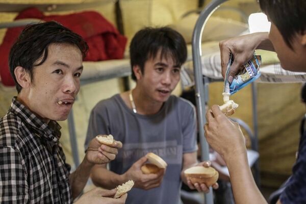 Вьетнамские мигранты обедают во временном лагере в Гольяново