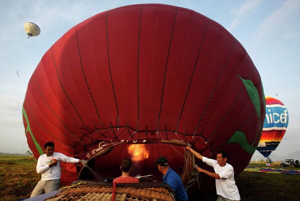 Участники наполняют воздушный шар горячим воздухом на Международном фестивале воздухоплавания на Филиппинах