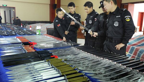 Китайские полицейские рассматривают изъятое оружие. Фото с места событий