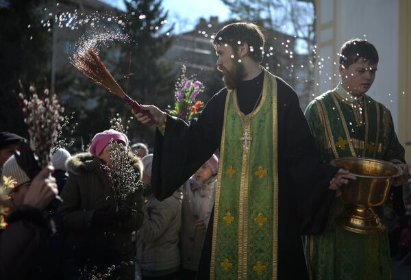 Священник освящает ветки вербы в праздник Входа Господня в Иерусалим у Вознесенского кафедрального собора в Новосибирске