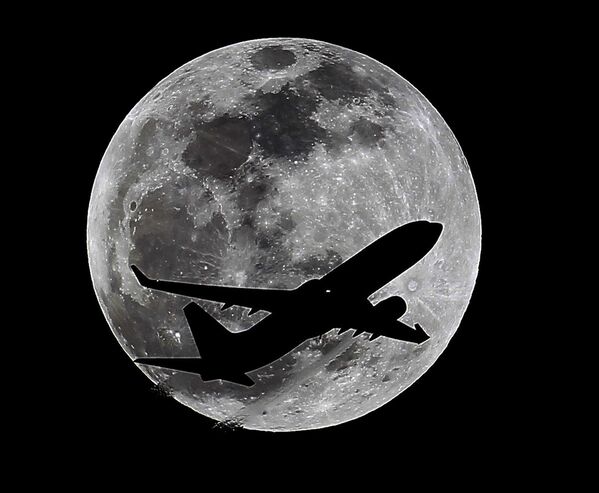 Самолет на фоне Луны за час до ее полного затмения над Калифорнией, США
