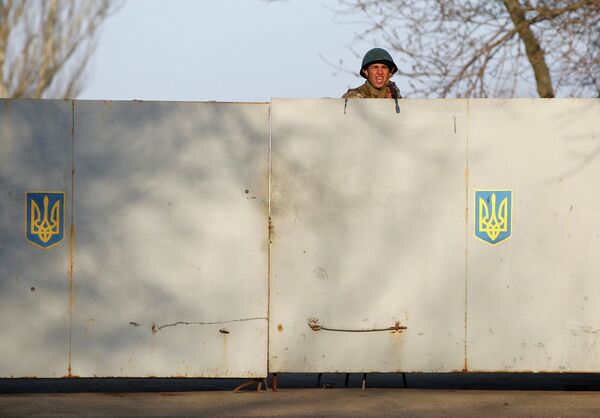 Украинский солдат целится из оружия в митингующих, которые собрались перед украинской авиабазой в Краматорске 15 апреля 2014