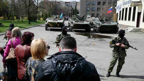 Местные жители стоят возле вооруженных людей, охраняющих БТР в Славянске