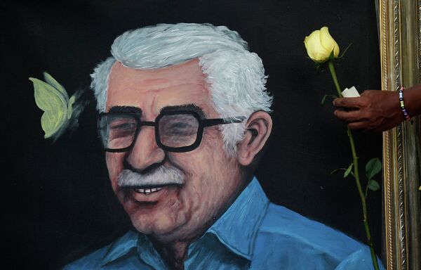 Житель держит розу перед плакатом c изображением Габриэля Гарсиа Маркеса