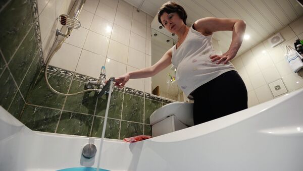 Женщина набирает воду в ванной комнате. Архивное фото