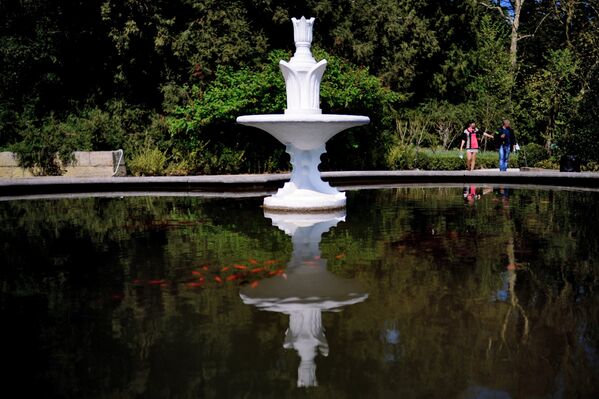 Прохожие гуляют у фонтана в Никитском ботаническом саду в поселке Никита неподалеку от города Ялта в Крыму