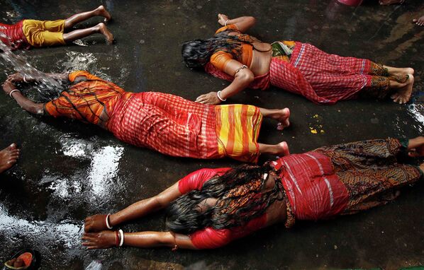 Женщины лежат на дороге во время ритуала поклонения богине Sheetala Mata
