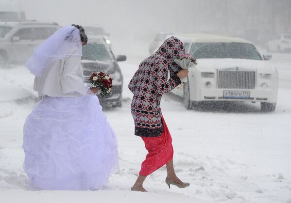 МНевеста идет по улице во время сильного снегопада в Челябинске