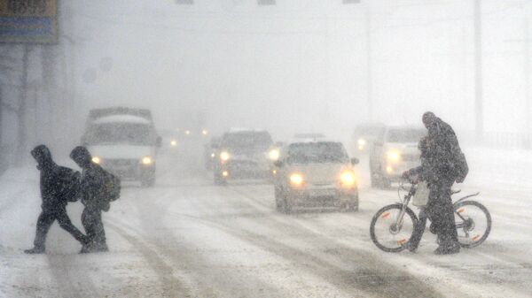 Пешеходы переходят дорогу во время сильного снегопада в Челябинске 