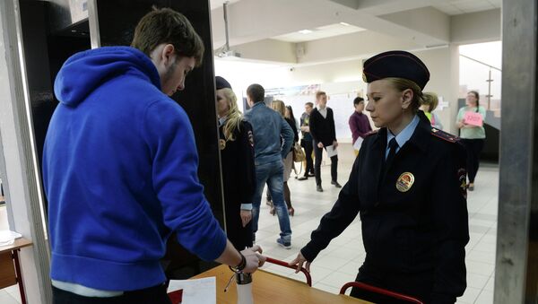 Сотрудники полиции досматривают личные вещи школьников перед входом в одну из московских школ для сдачи ЕГЭ.