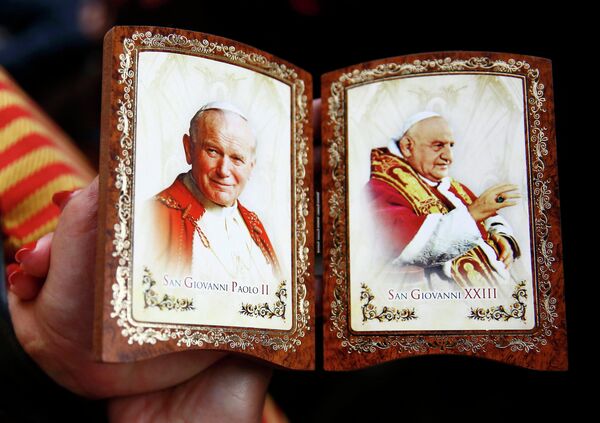 Католик держит сувенир с изображением папы Иоанна Павла II во время церемонии канонизации в Ватикане