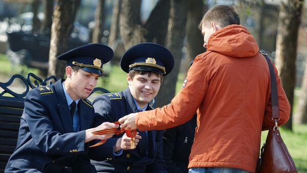 Волонтер раздает ленточки на площади у мемориала Вечный огонь Славы в Иркутске