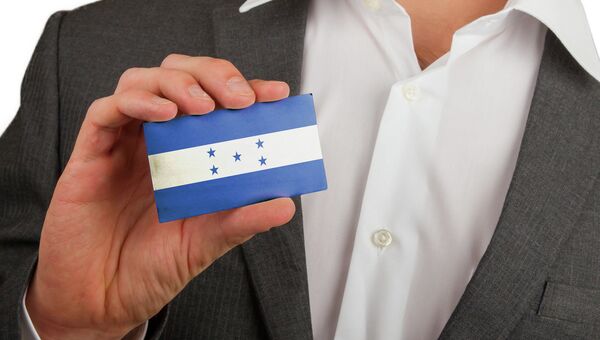Мужчина держит карточку с флагом Гондураса. Архивное фото