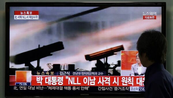 Мужчина на вокзале в Сеуле смотрит выпуск новостей о военных учениях КНДР