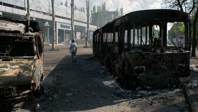 Мужчина проходит мимо сожженных автомобилей в городе Краматорске