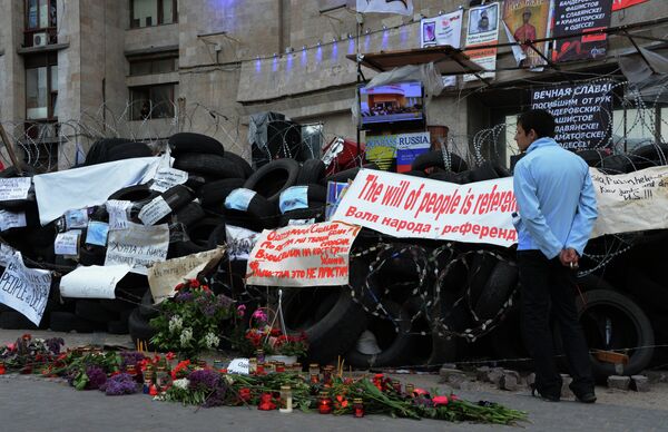 Цветы и свечи в память о погибших в Одессе у окруженного баррикадами здания областной государственной администрации города Донецка