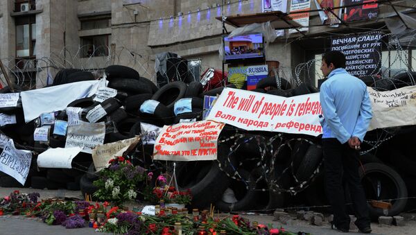 Цветы и свечи в память о погибших в Одессе у окруженного баррикадами здания областной государственной администрации города Донецка