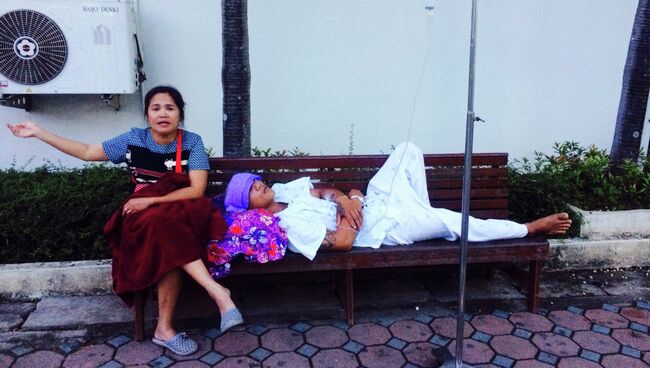 Женщина рядом с эвакуированным из больницы пациентом во время землетрясения в Таиланде