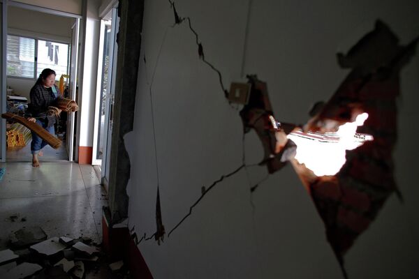 Женщина выносит вещи из дома, поврежденного в результате землетрясения в Таиланде