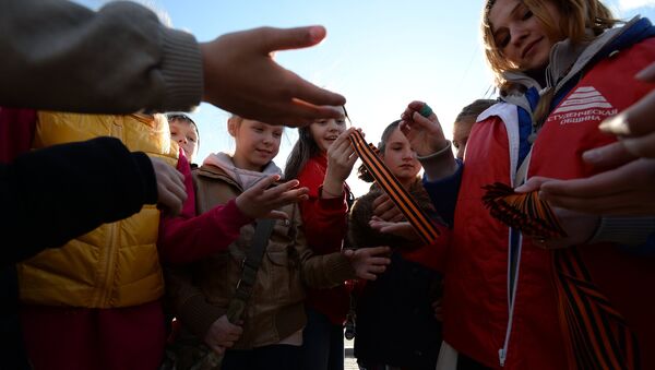 Волонтер раздает георгиевские ленточки детям на Поклонной горе в Москве. Архивное фото