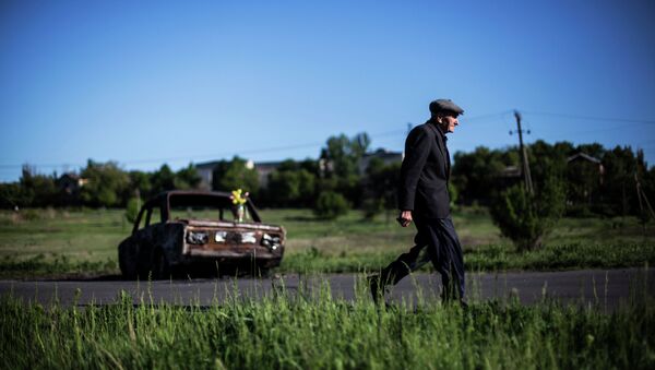Мужчина проходит возле сгоревшего автомобиля на месте столкновения народного ополчения и укринской армии возле Славянска