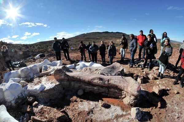 Люди стоят возле костей динозавтра недалеко от аргентинского города Трелью