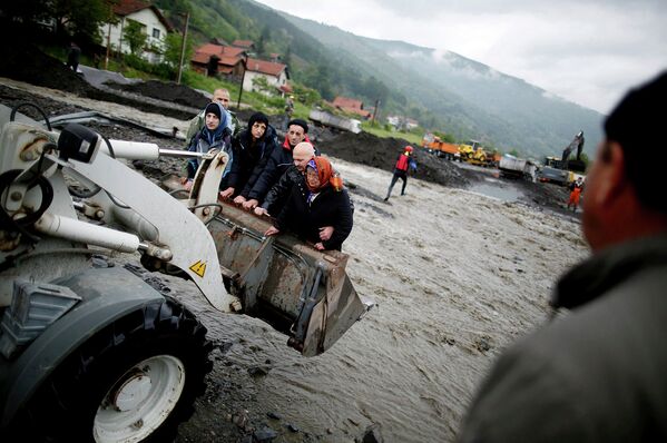 Люди переносятся фронтальным погрузчиком, во время эвакуации недалеко от города Жепче