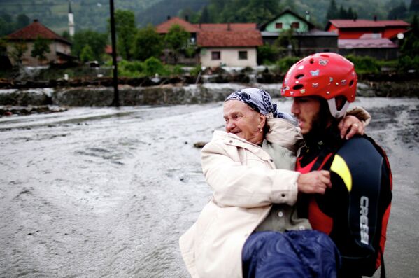 Член спасательной команды несет на руках женщину во время эвакуации недалеко от города Жепче